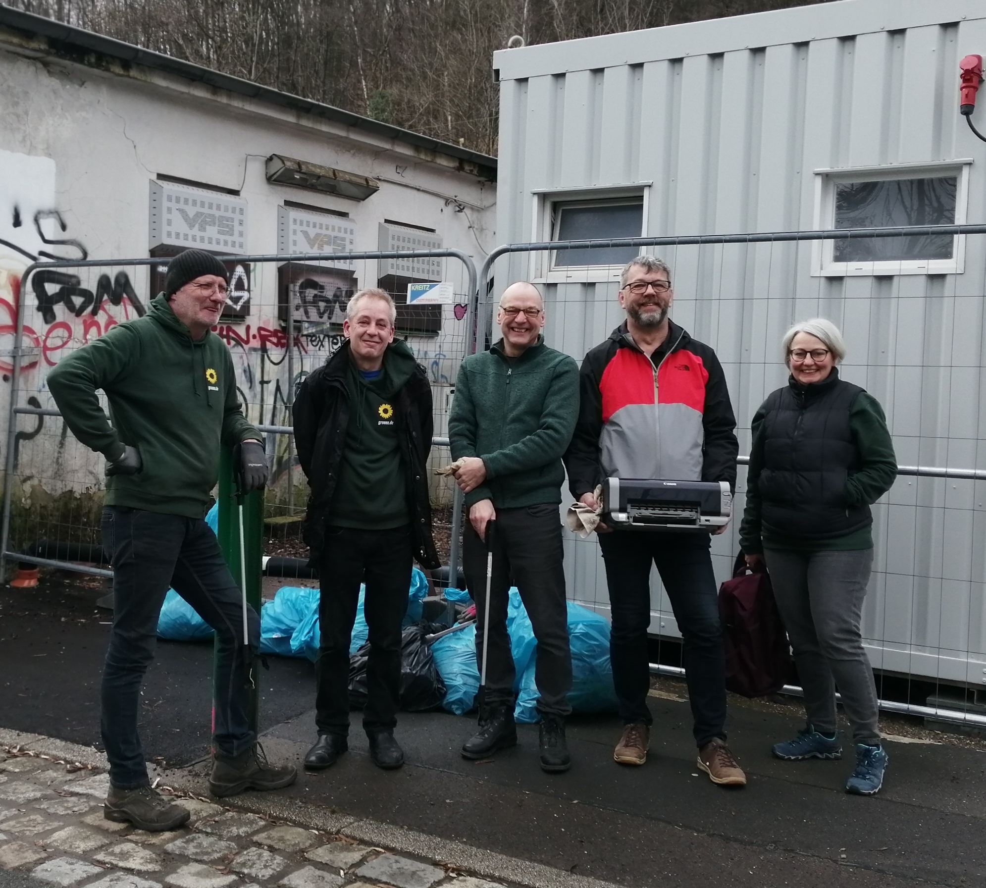 Fünf Personen stehen vor einem Container und lächeln während eines Frühjahrsputzes am Bahnhof Ennepetal.